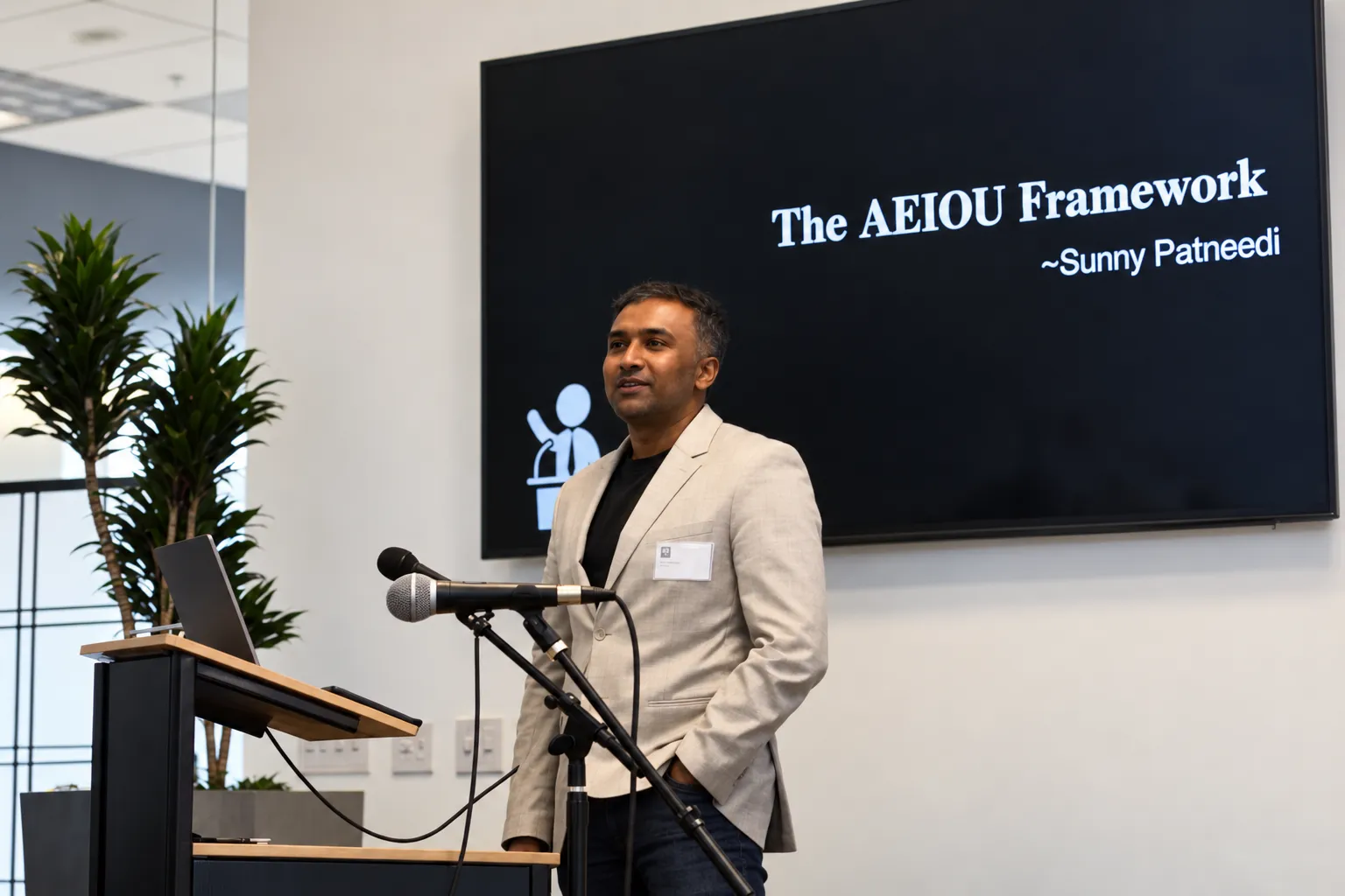Sunny Patneedi speaking in front of a screen showing the AEIOU Framework
